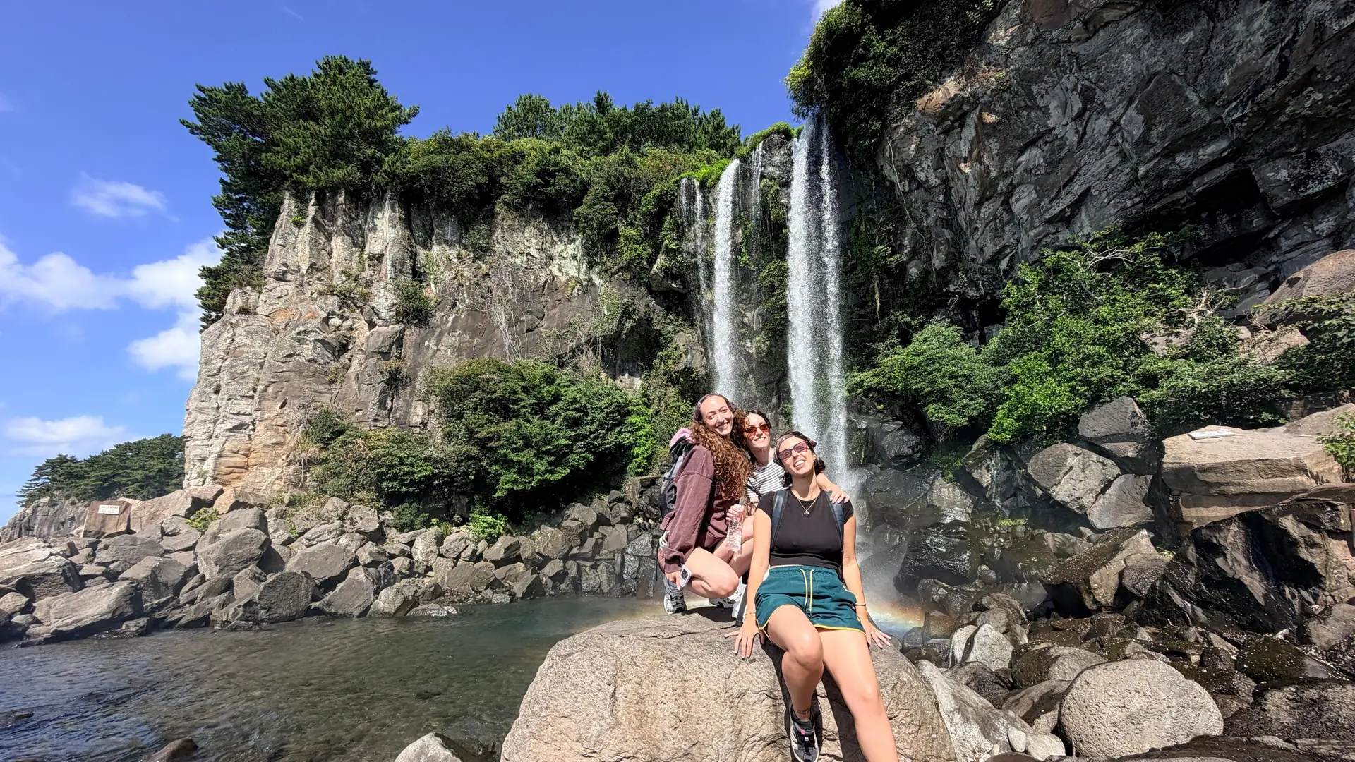 Visitors on the boulders below Jeongbang Falls, from the South Jeju day tour listing
